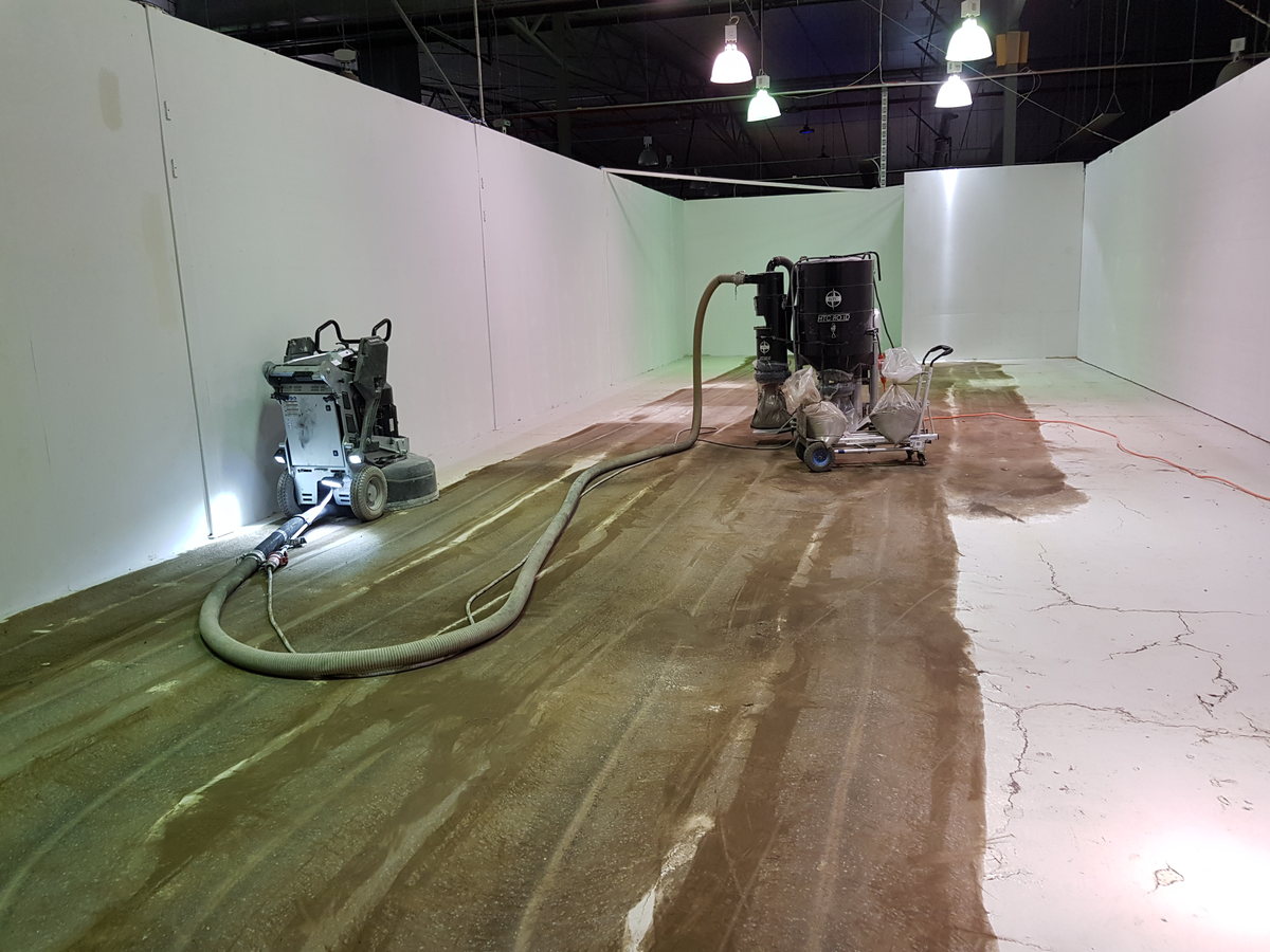 Existing concrete slab part-way through grinding, with old coating removed from one section and still in place on another