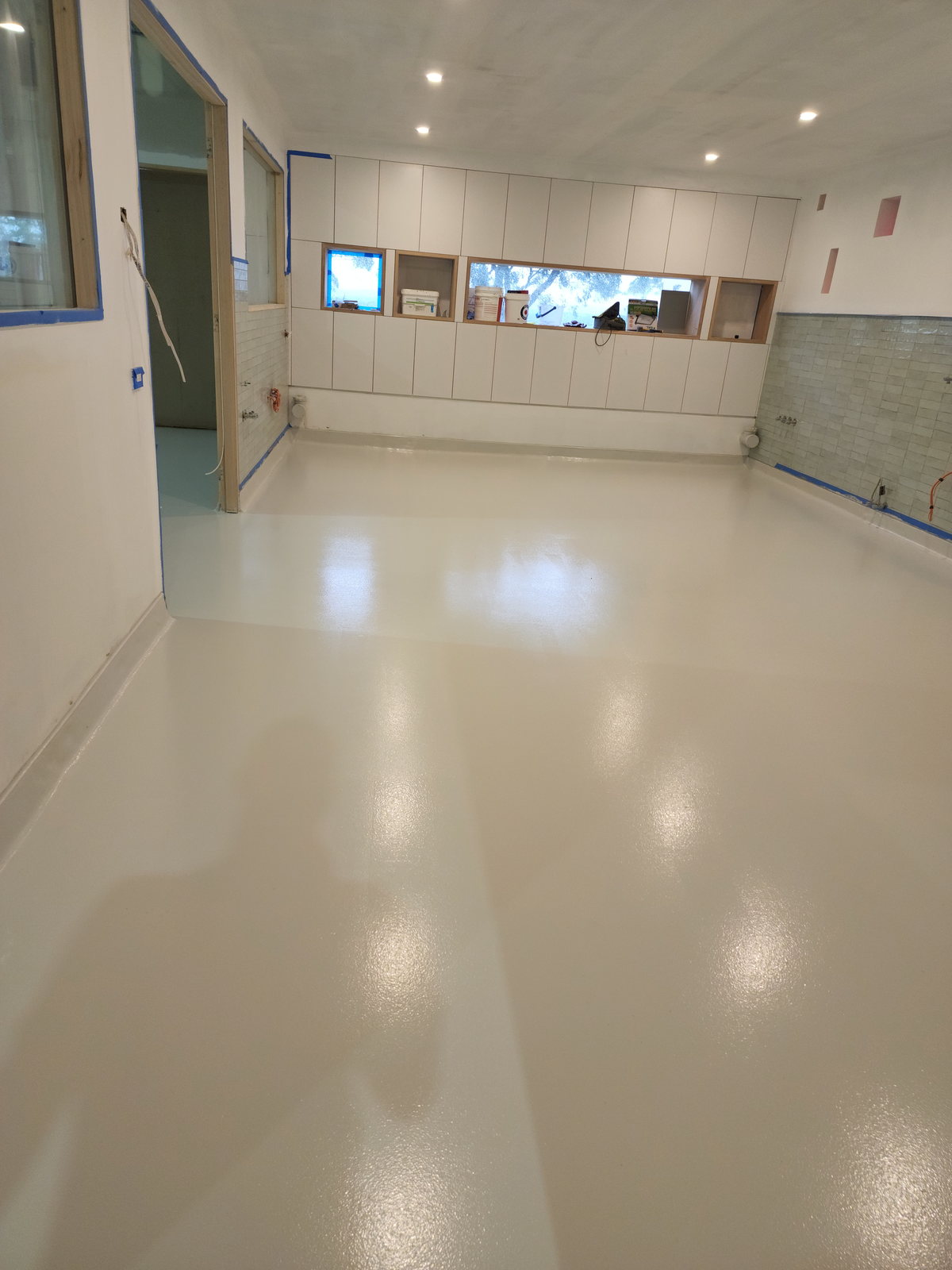Cream epoxy floor in a commercial kitchen with servery windows along one wall