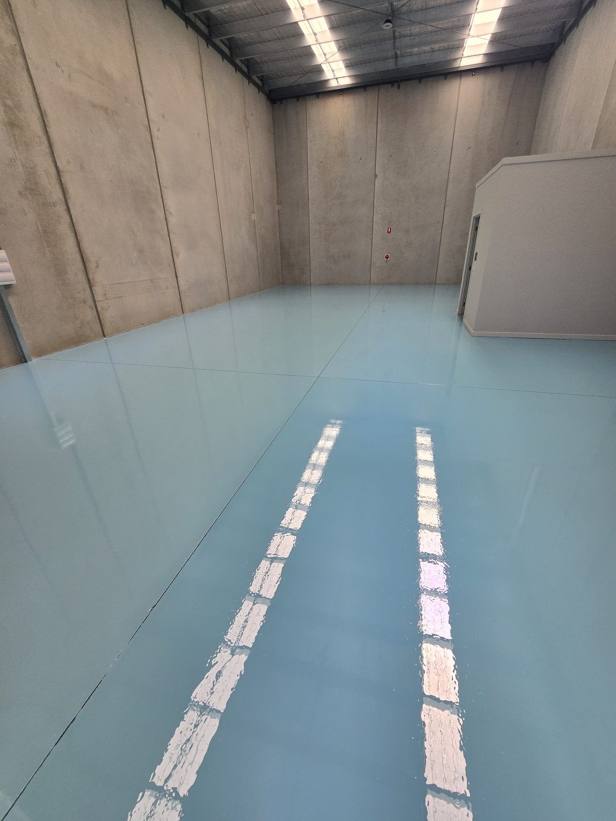 Epoxy-coated floor with painted safety line marking, an application the article compares with polished concrete