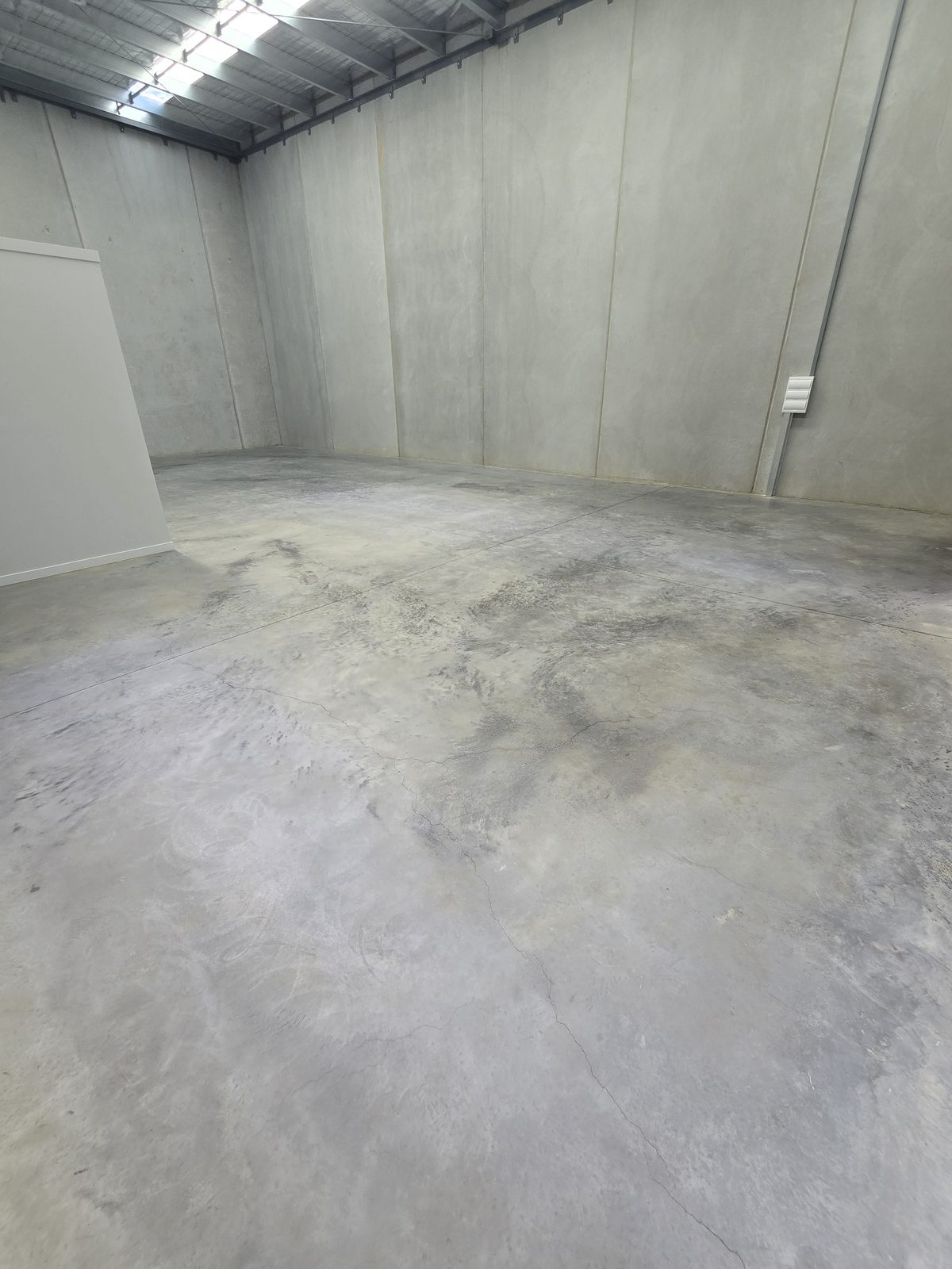 Sealed concrete floor keeping its natural matte appearance in an empty industrial unit with precast concrete walls