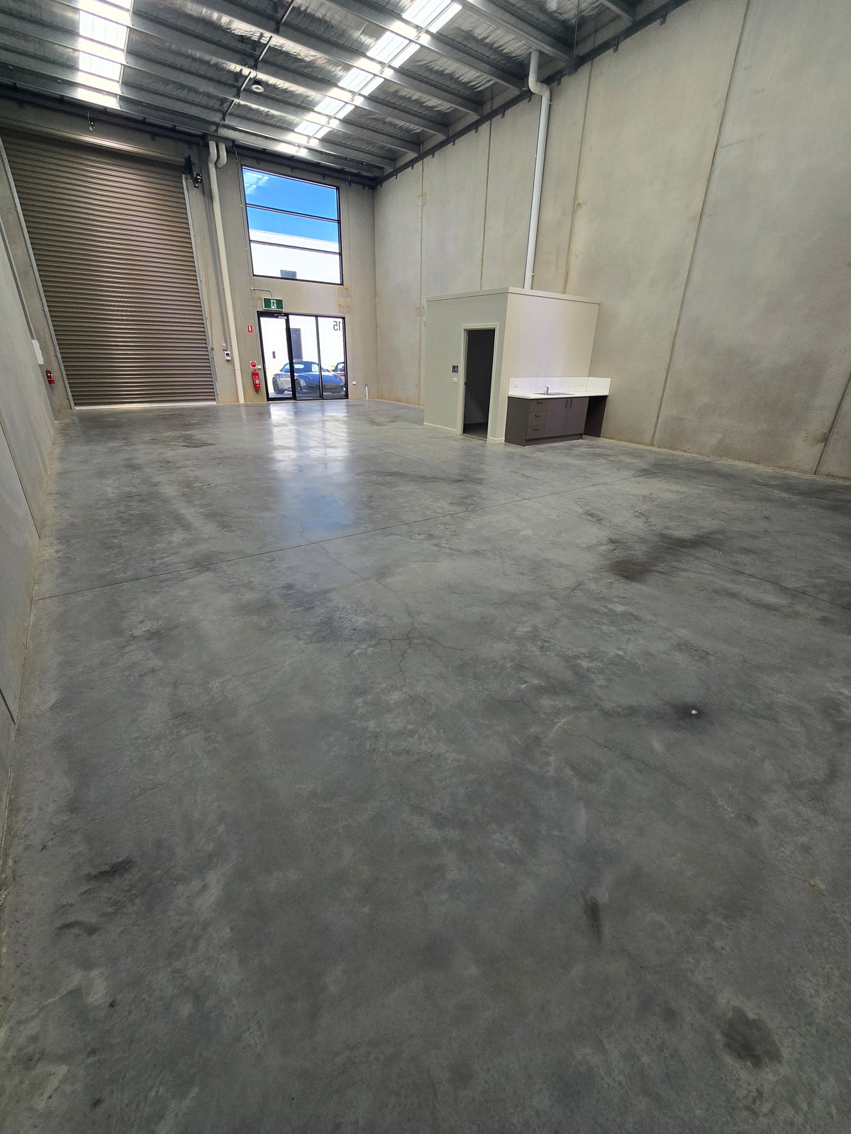Dust-sealed concrete warehouse floor showing an even low sheen across the bay