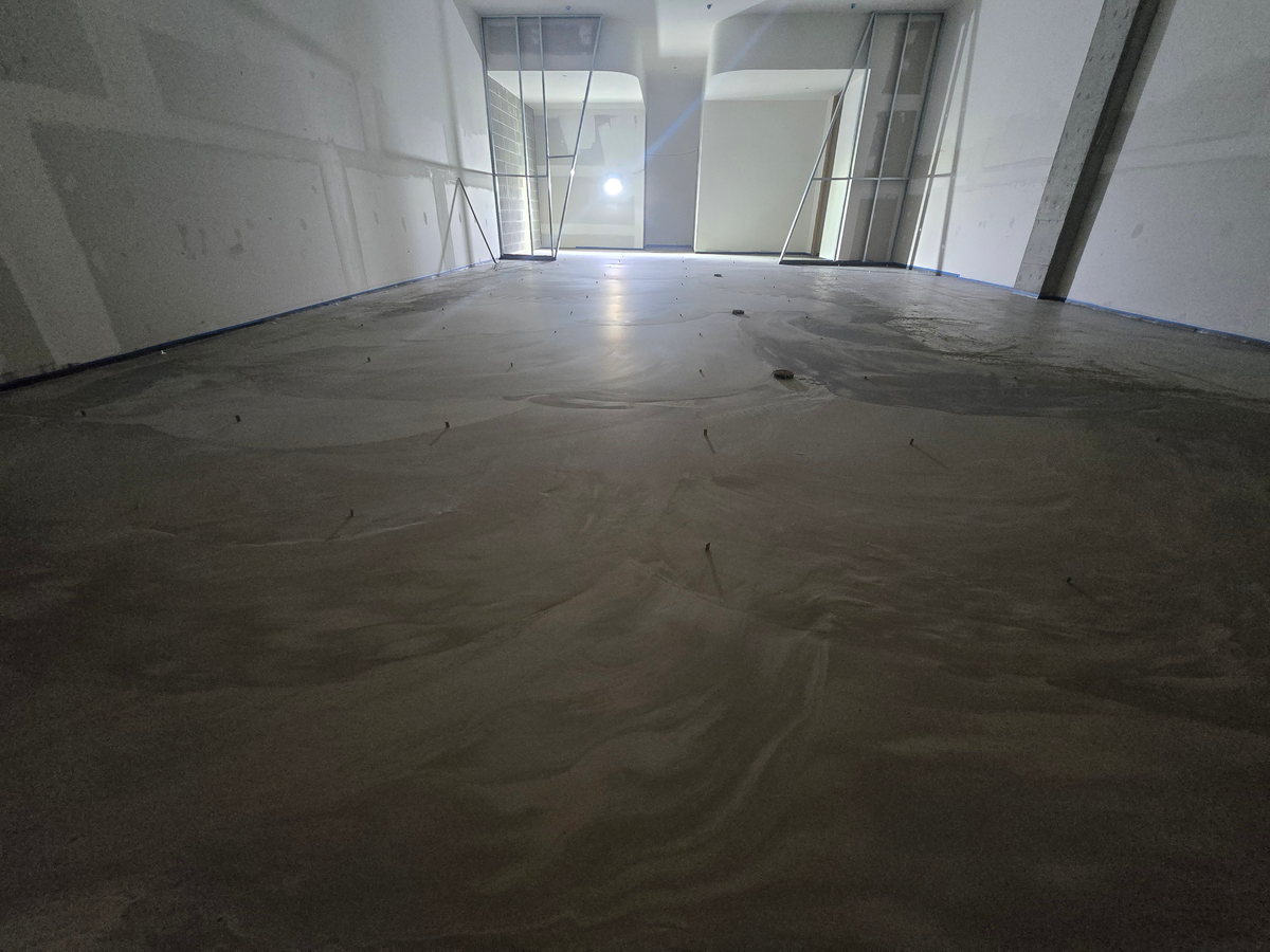 Freshly poured levelling screed across a floor being prepared before finishing