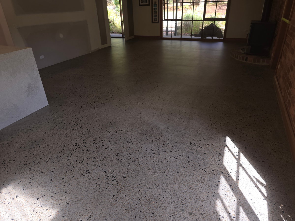 Charcoal grind-and-seal floor in a sunlit open living area