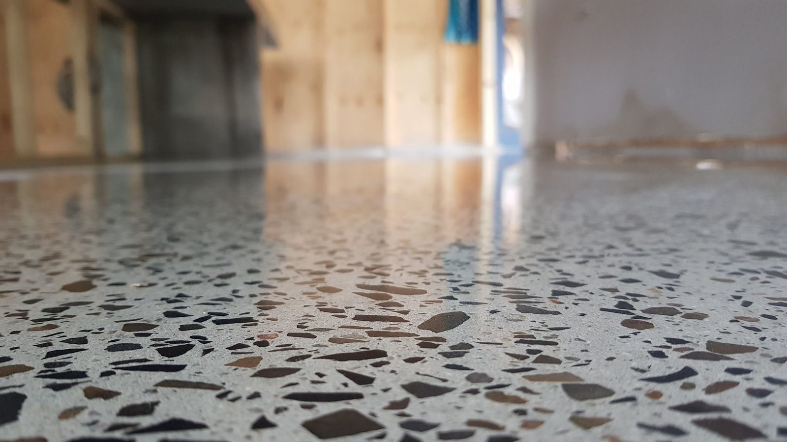 Low-angle view of a mirror-finish polished concrete floor with dense exposed aggregate in a finished garage conversion