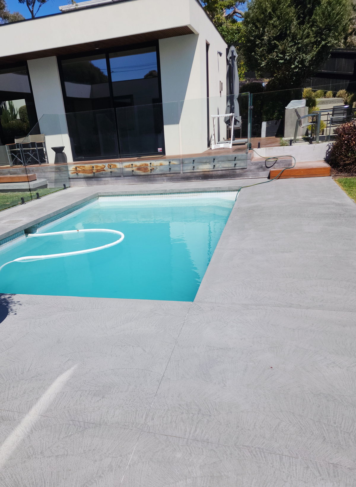 Textured Rasico concrete finish surrounding an outdoor swimming pool.