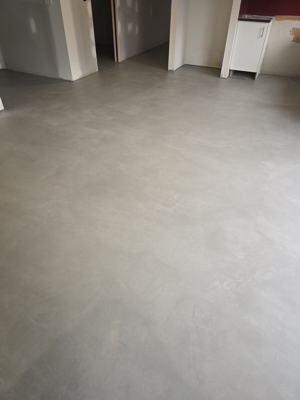 Seamless microcement finish running continuously across both the floor and wall of a room