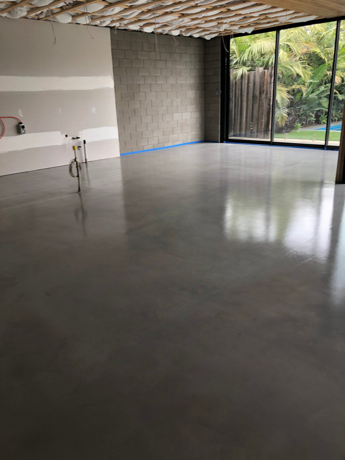 Grey micro-topping floor reflecting light from full-height glazing onto a garden