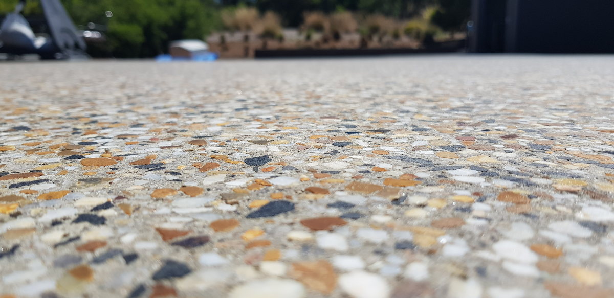 Close-up of an exposed-aggregate pavilion finish showing multicoloured pebbles in sunlight