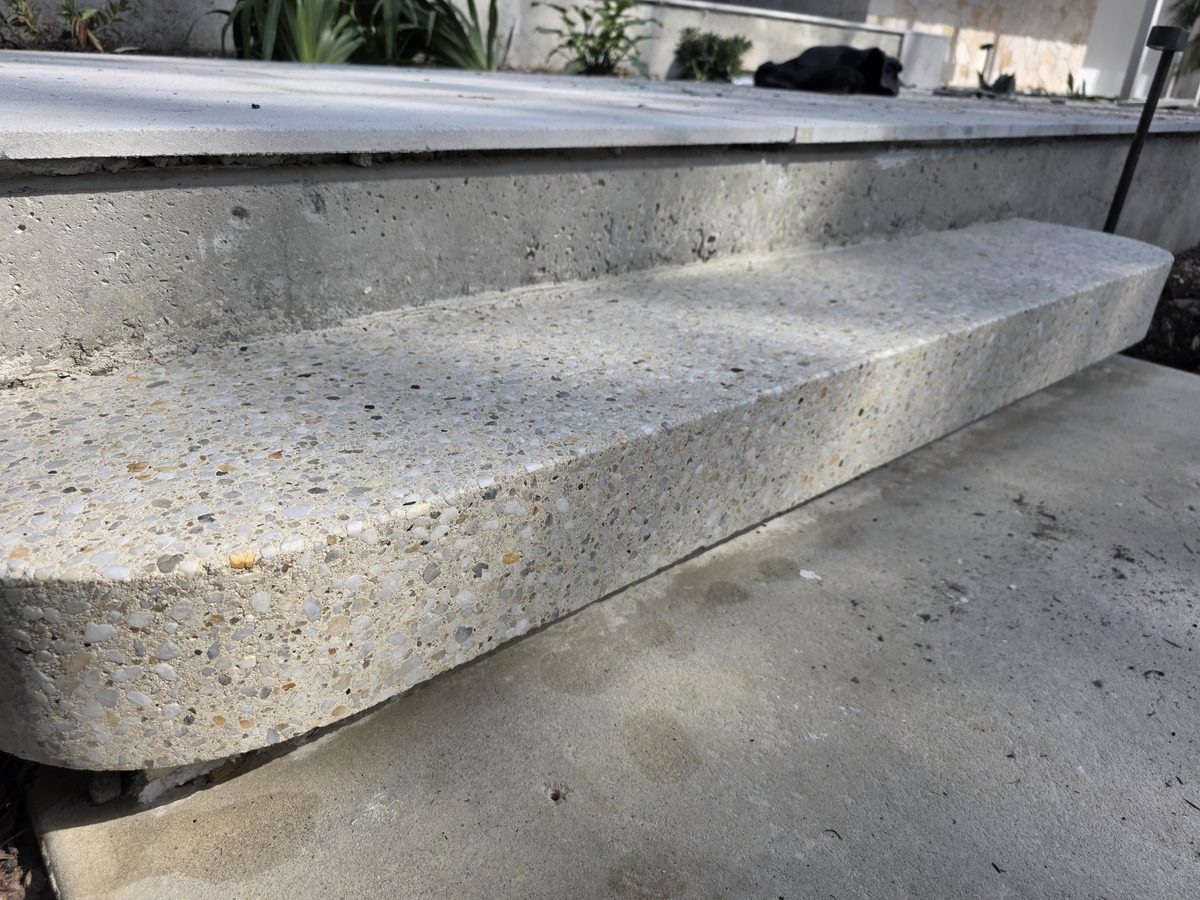 Textured exposed-aggregate finish on a bullnose step edge, a surface specified where grip matters