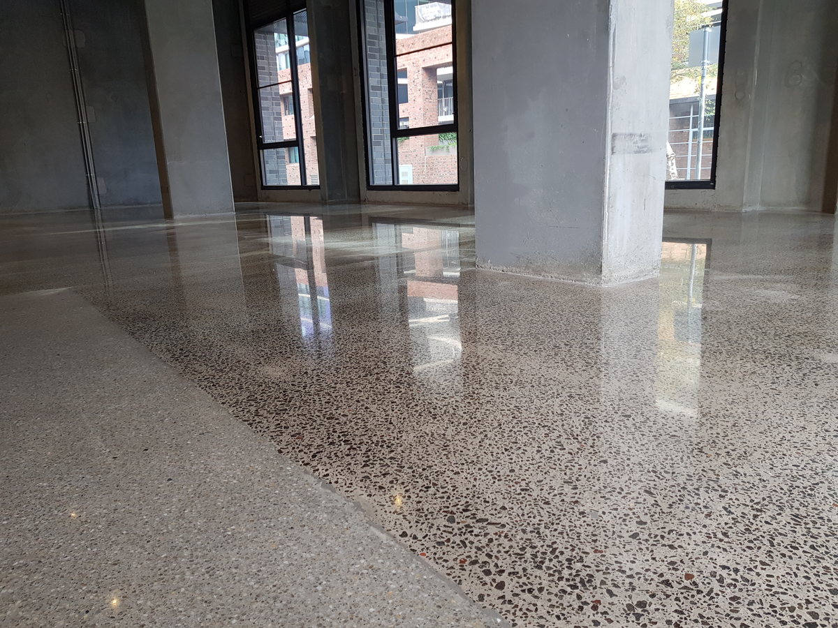 Polished concrete floor in an open commercial space with a square column and full-height windows