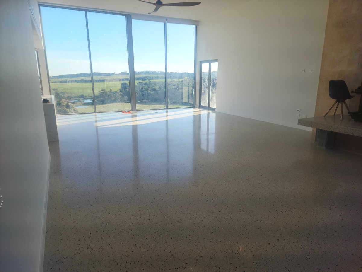 Polished concrete living-room floor reflecting full-height windows that overlook farmland