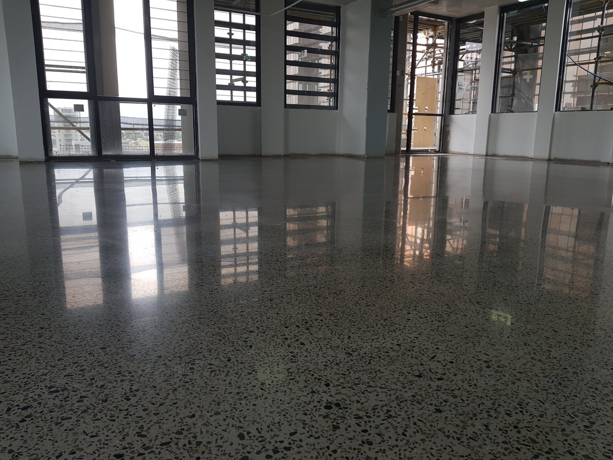 Wide view of a polished concrete office floor reflecting a full wall of windows