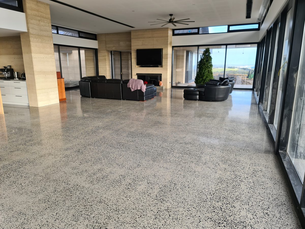 Polished concrete floor reflecting natural light in a large open-plan living area