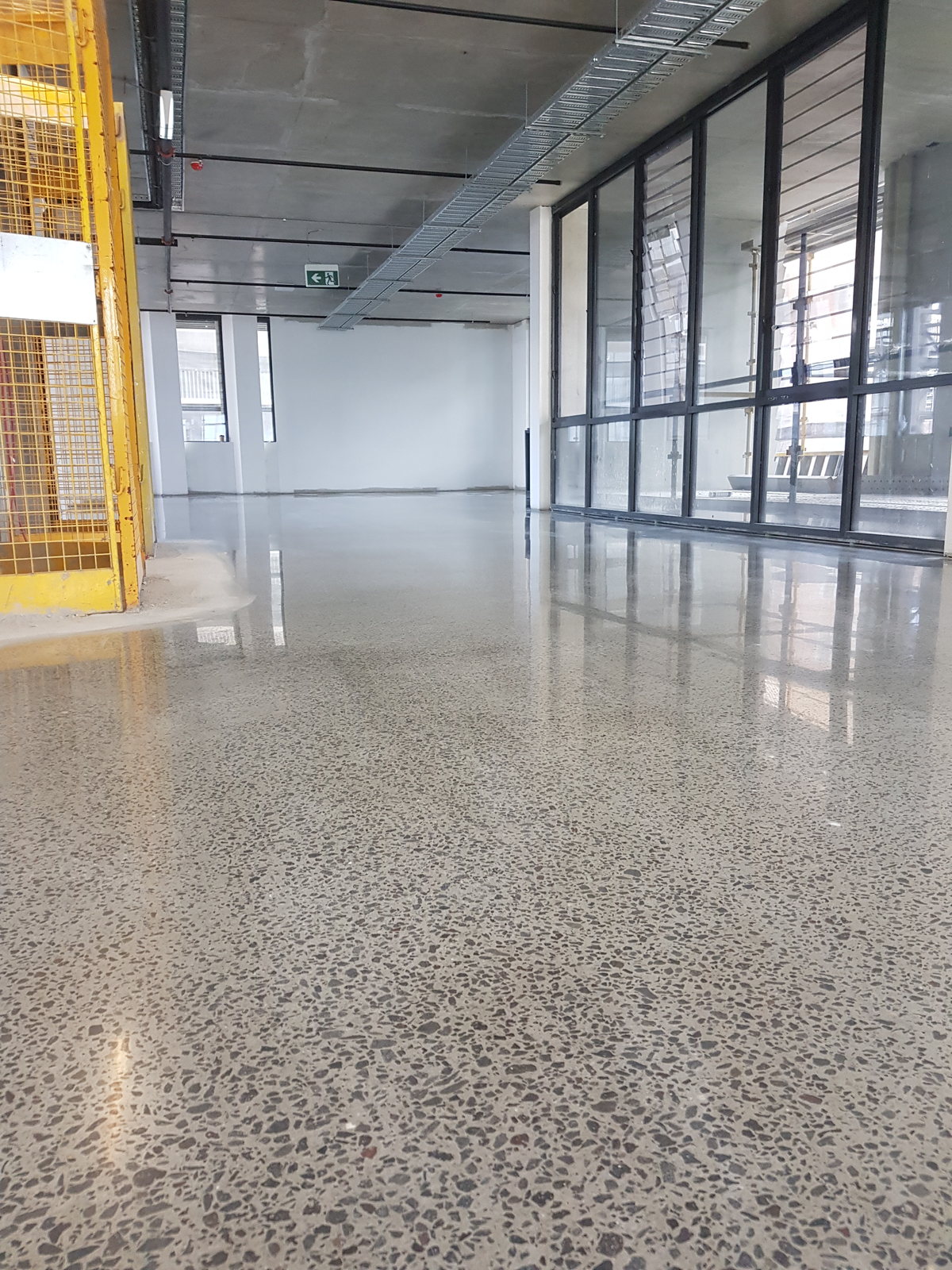 Bright open-plan office with a light speckled polished concrete floor and glazed partitions