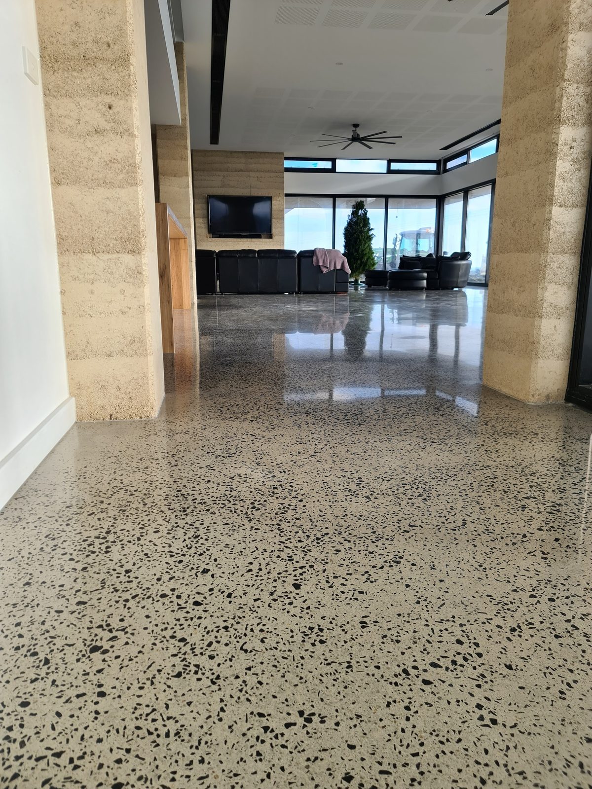 Wide view of a mechanically polished concrete floor running consistently through a large open-plan living area